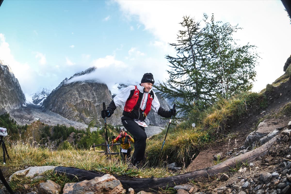 Runners climbing an alpine trail with poles at UTMB