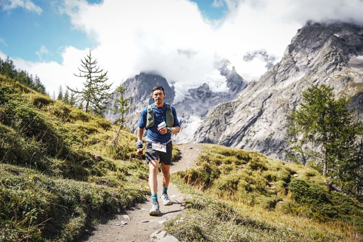 Solo runner on an alpine trail with glacier backdrop